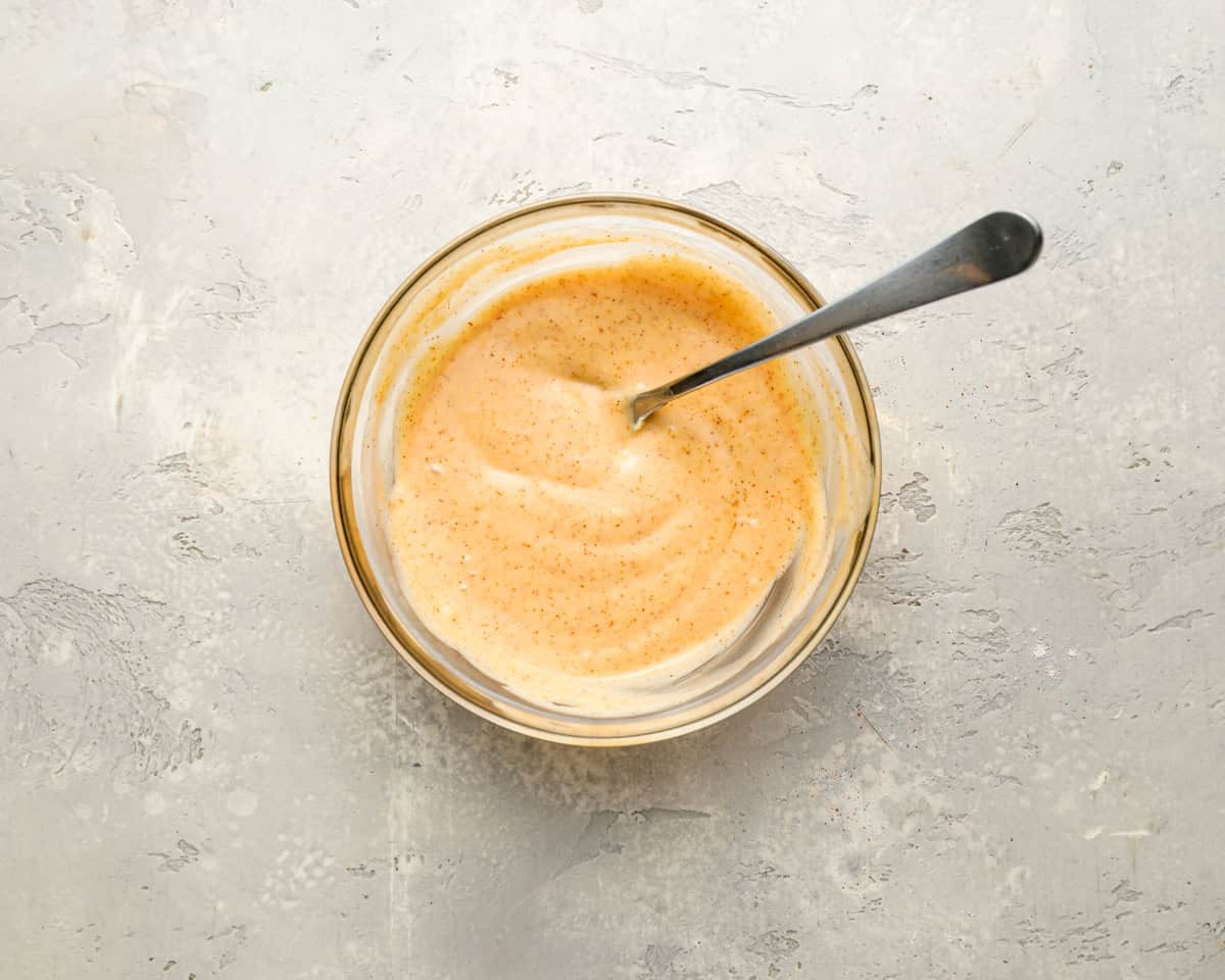 spicy orange mayonnaise in a glass bowl with a spoon.