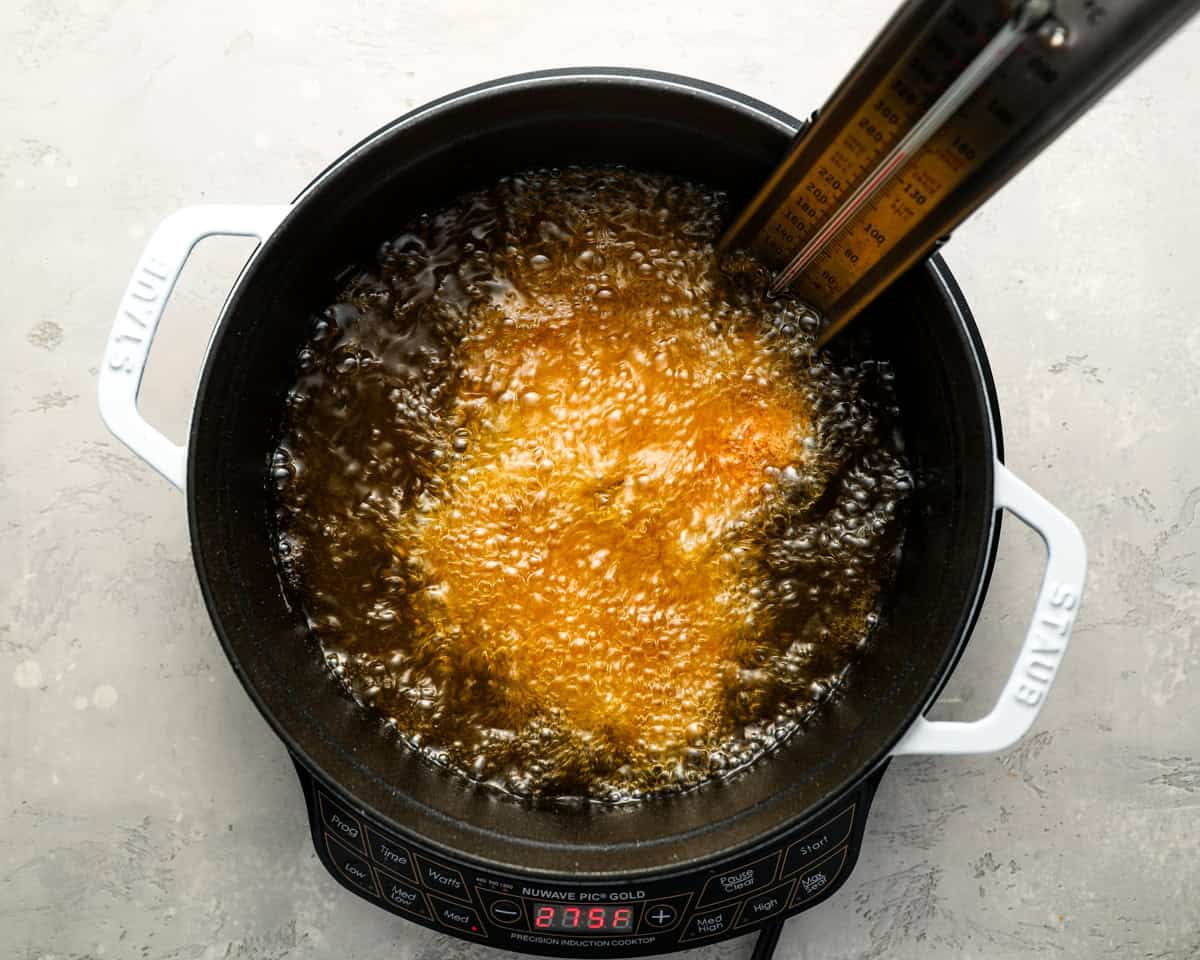 deep frying a chicken thigh in a dutch oven.