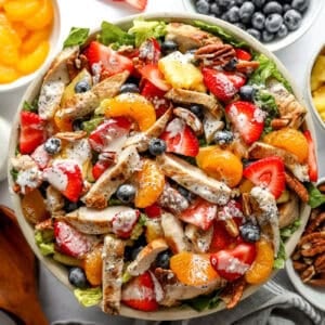 overhead view of a dressed strawberry poppyseed chicken salad in a large bowl.