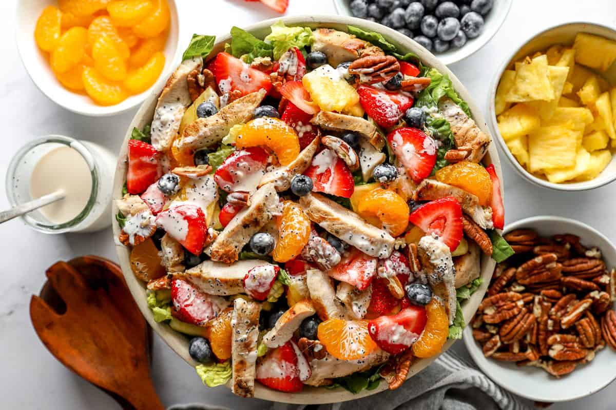 overhead view of a dressed strawberry poppyseed chicken salad in a large bowl.