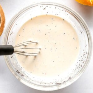 poppyseed dressing in a glass bowl with a whisk.