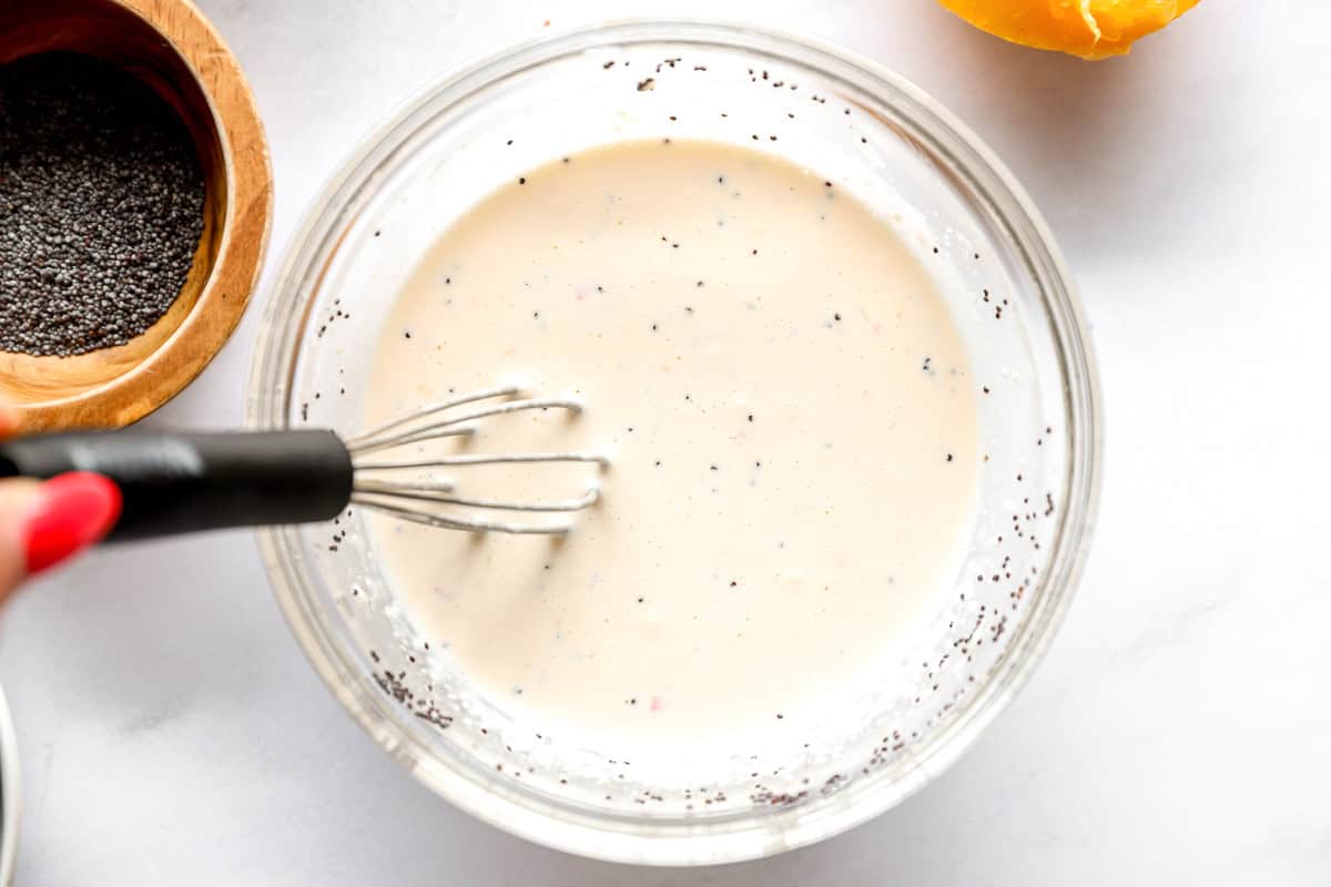 poppyseed dressing in a glass bowl with a whisk.