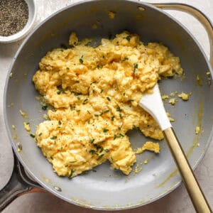 scrambled eggs in a pan with a rubber spatula.