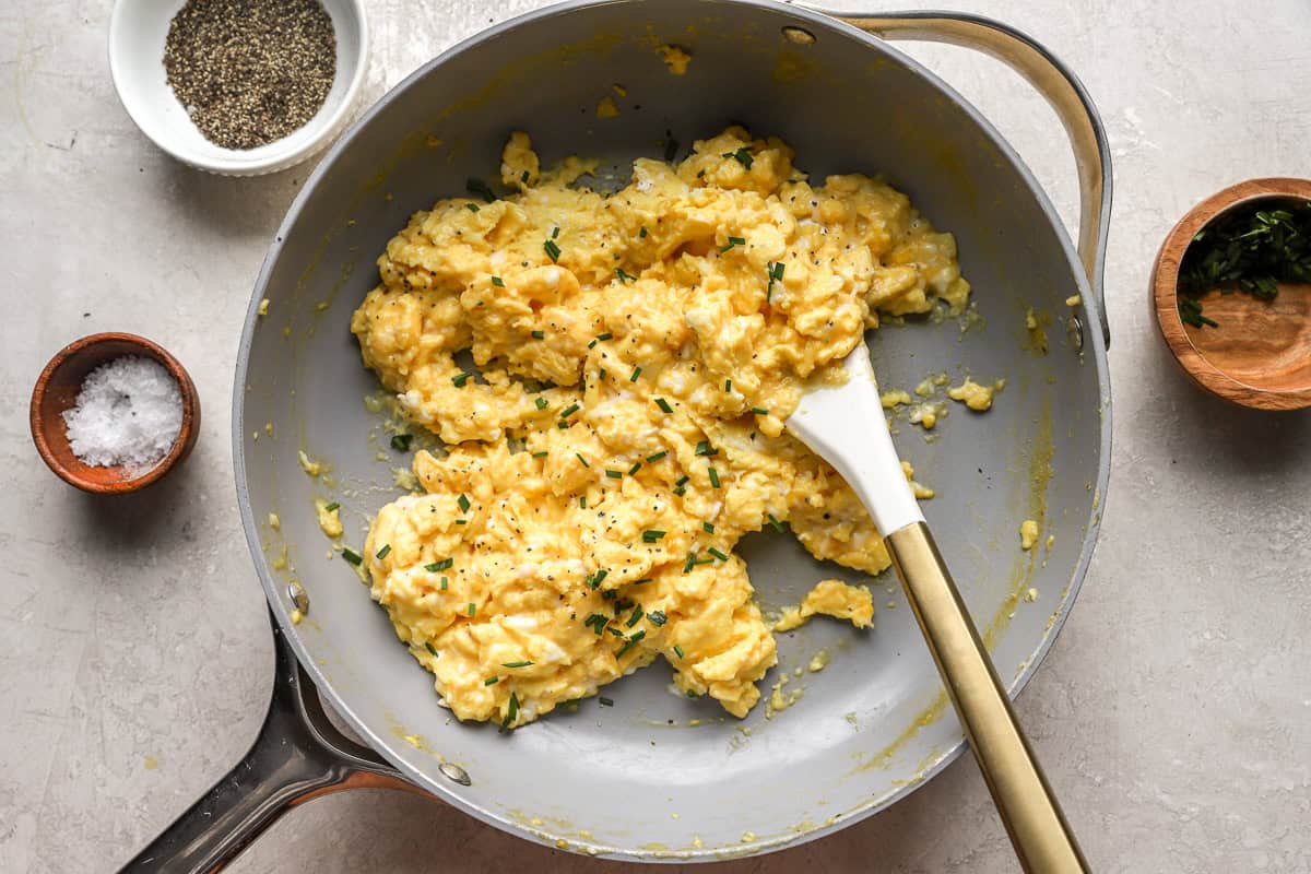 scrambled eggs in a pan with a rubber spatula.