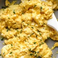 closeup of scrambled eggs in a pan with a rubber spatula.