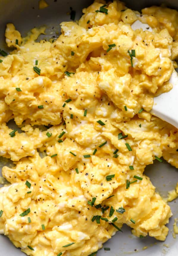 closeup of scrambled eggs in a pan with a rubber spatula.