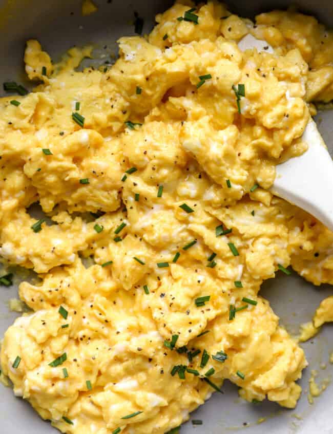 closeup of scrambled eggs in a pan with a rubber spatula.