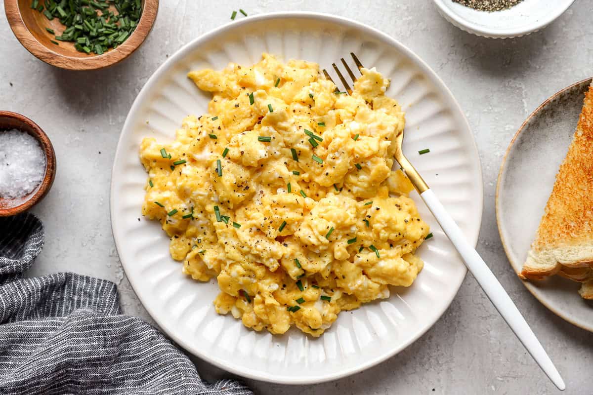 overhead view of scrambled eggs on a white plate with a fork.