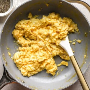 soft set scrambled eggs in a pan with a rubber spatula.