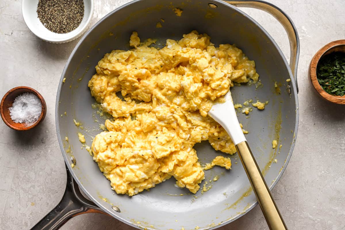 soft set scrambled eggs in a pan with a rubber spatula.