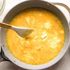 scrambling eggs in a pan with a rubber spatula.