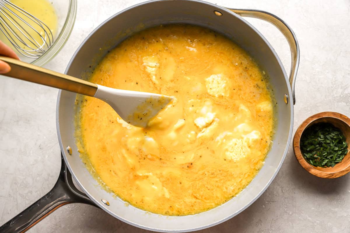 scrambling eggs in a pan with a rubber spatula.