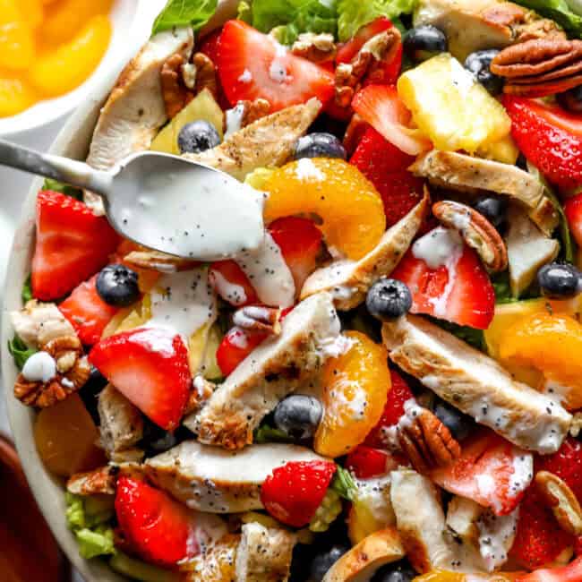 closeup overhead view of strawberry poppyseed chicken salad in a bowl with a spoon.