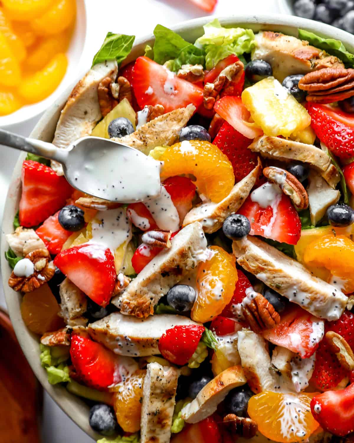 closeup overhead view of strawberry poppyseed chicken salad in a bowl with a spoon.