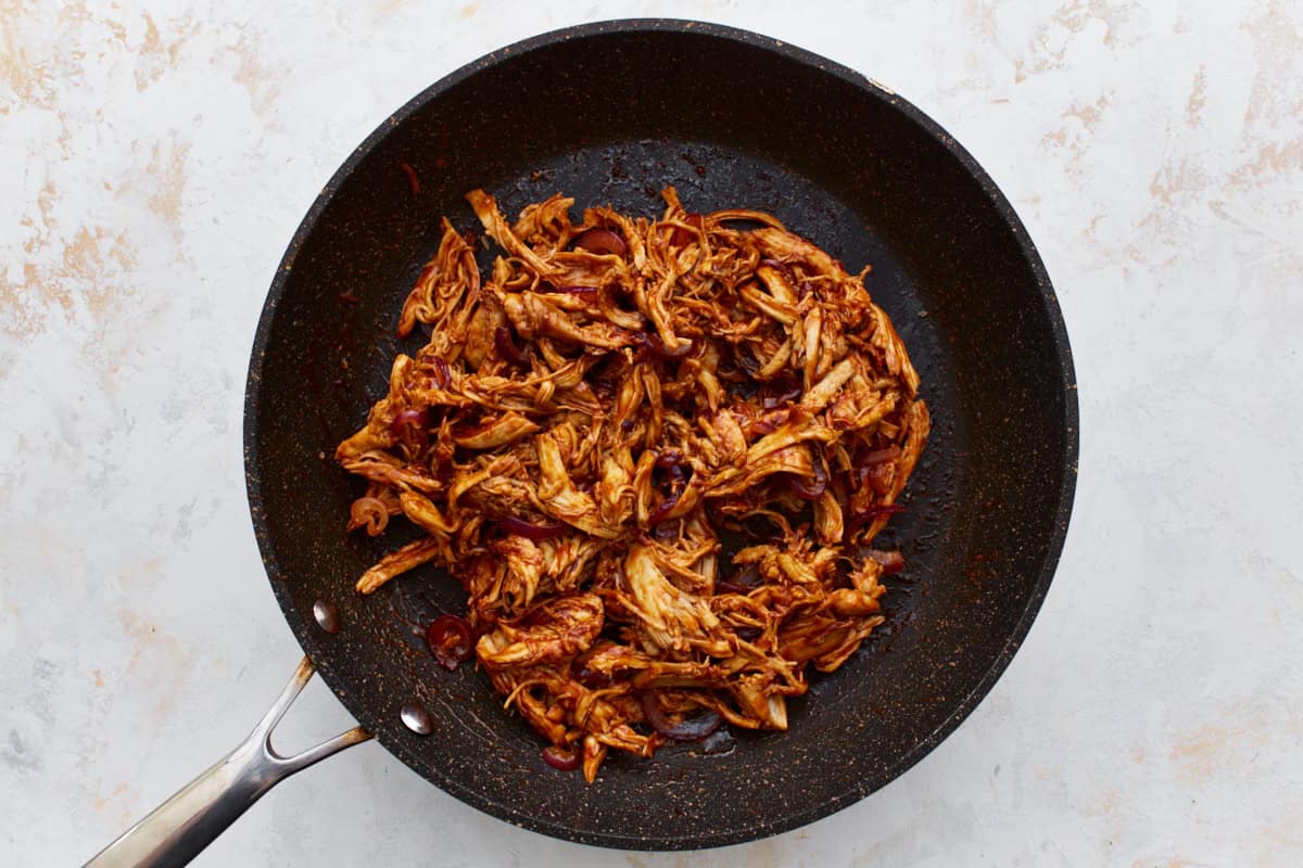 bbq shredded chicken and onions in a pan.