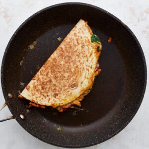 a cooked folded half-moon quesadilla in a pan.