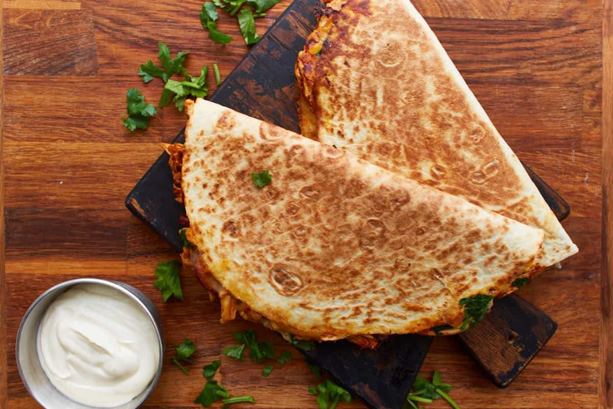 2 bbq chicken quesadillas on a cutting board.