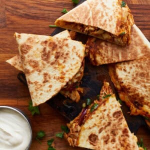 bbq chicken quesadillas cut into wedges on a cutting board.