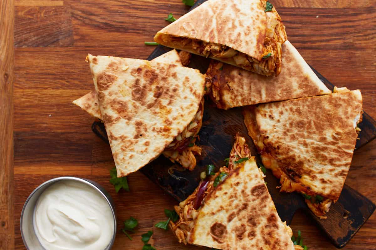 bbq chicken quesadillas cut into wedges on a cutting board.