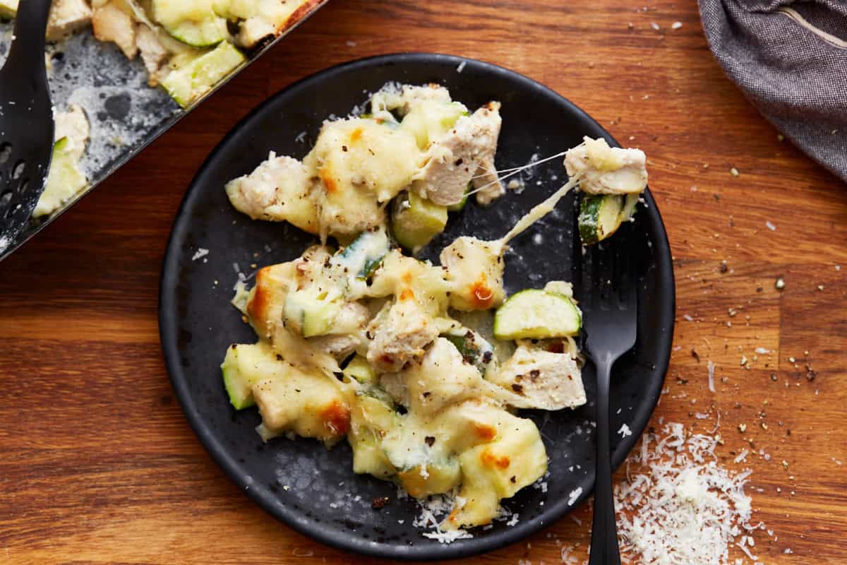 a serving of chicken zucchini casserole on a black plate with a fork.