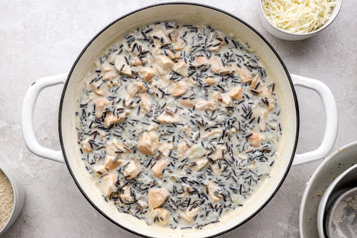 Chicken, wild rice, and creamy sauce combined in a large pot.