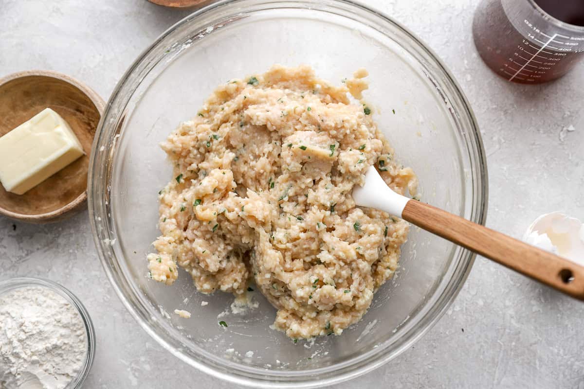 Combining ground chicken with meatball ingredients.