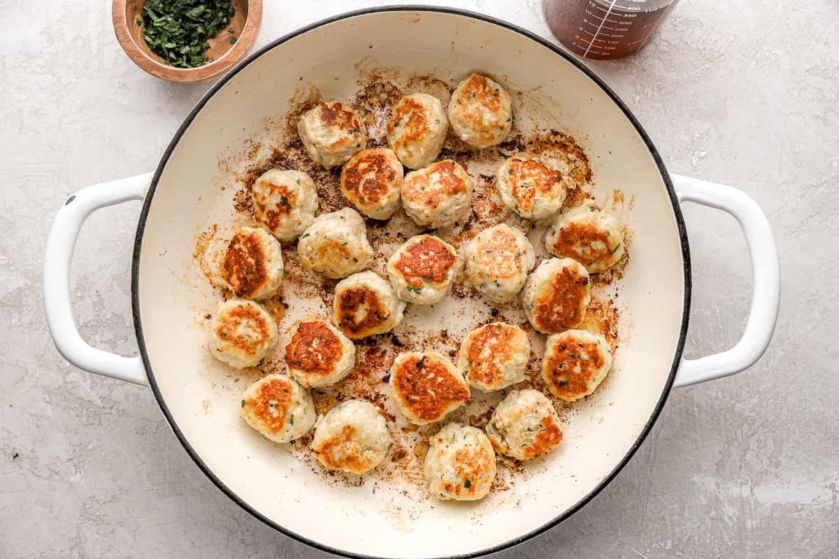 Ground chicken meatballs in a pot.