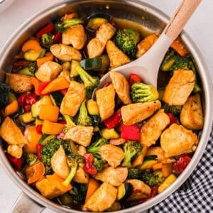 overhead view of honey soy chicken stir fry in a pan with a spoon.