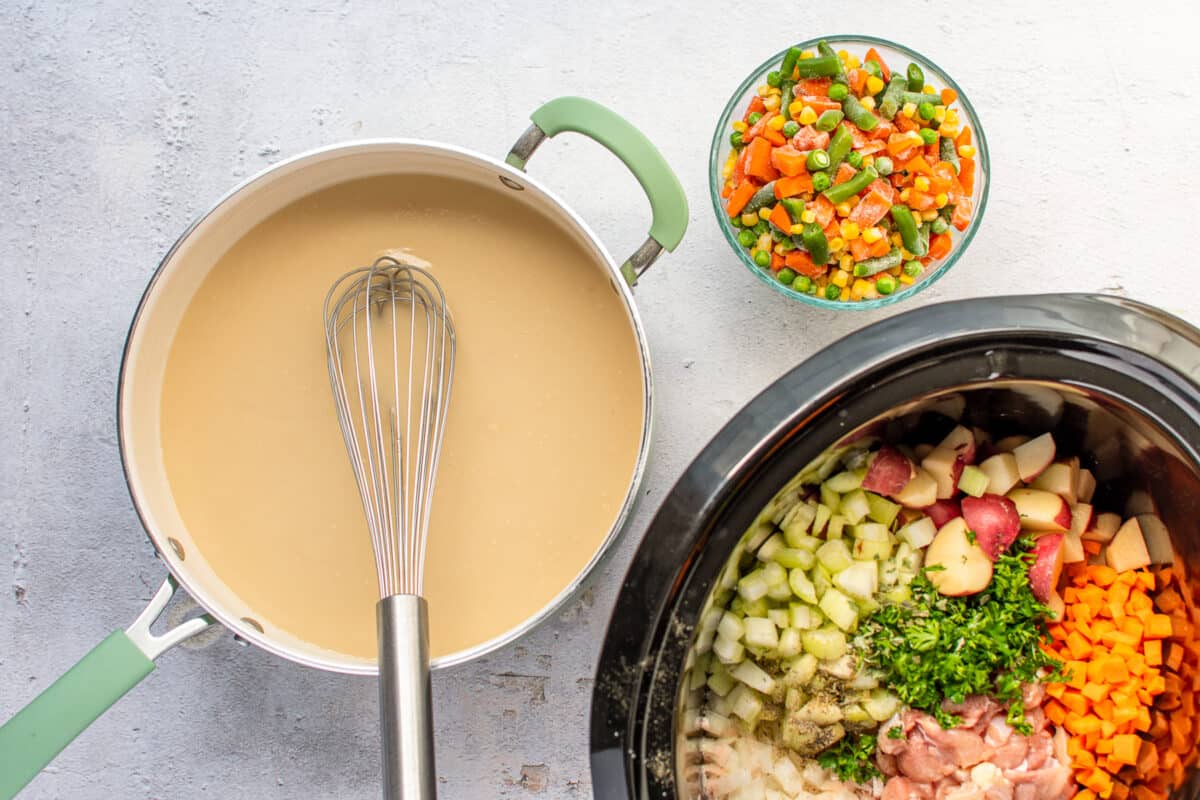 Creamy roux in a saucepan, next to a Crockpot filled with diced veggies and other ingredients.