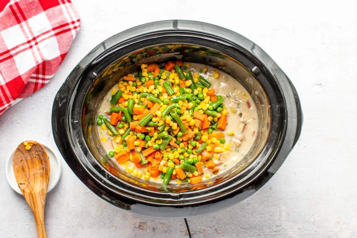 Mixed veggies poured on top of filling, in a slow cooker.