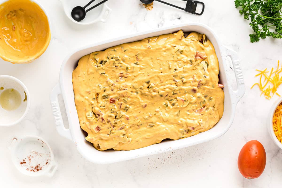 Chicken topped with queso in a baking dish.