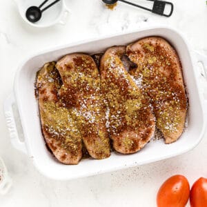 4 chicken breasts in a baking dish, covered with a variety of spices.