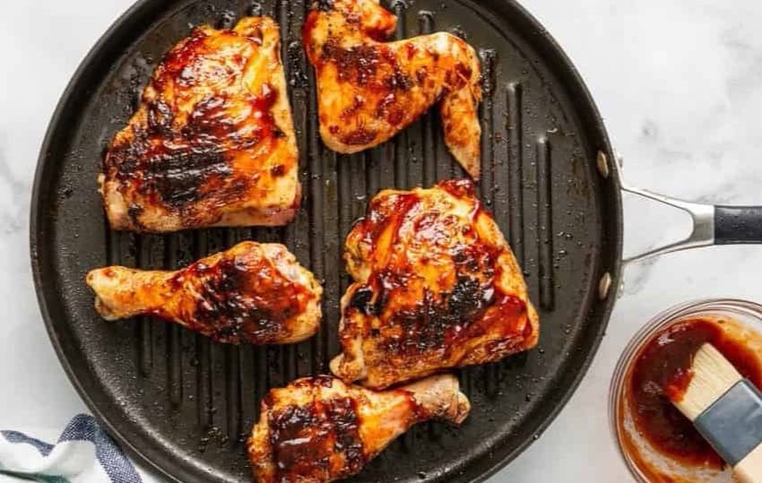 BBQ chicken cooking on a grill pan.