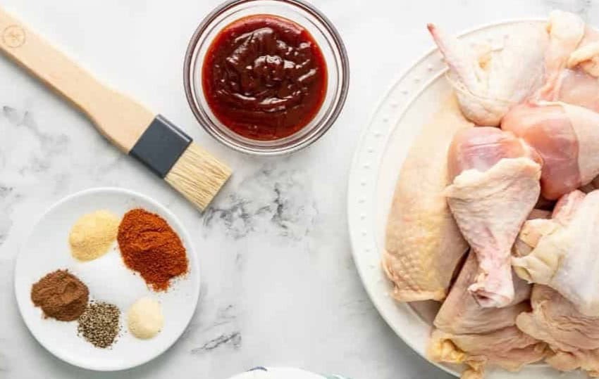 ingredients for grilled BBQ chicken arranged on a marble counter top.