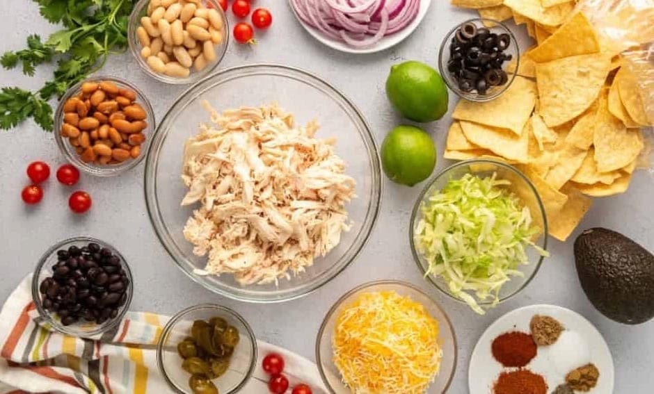 ingredients for Mexican chicken nachos arranged in bowls.