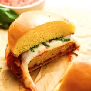 a halved chicken parmesan burger on a bun.