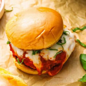a chicken parmesan burger on crinkled parchment paper.