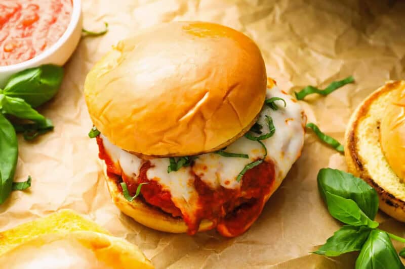 a chicken parmesan burger on crinkled parchment paper.