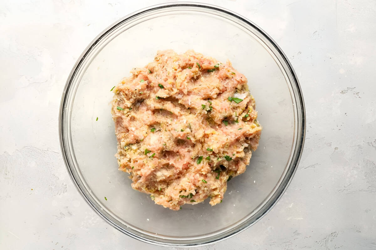 breadcrumb-filled ground chicken patty mixture in a glass bowl.