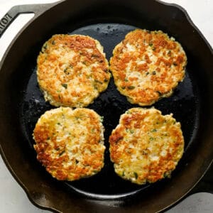 4 cooked ground chicken burger patties in a cast iron pan.