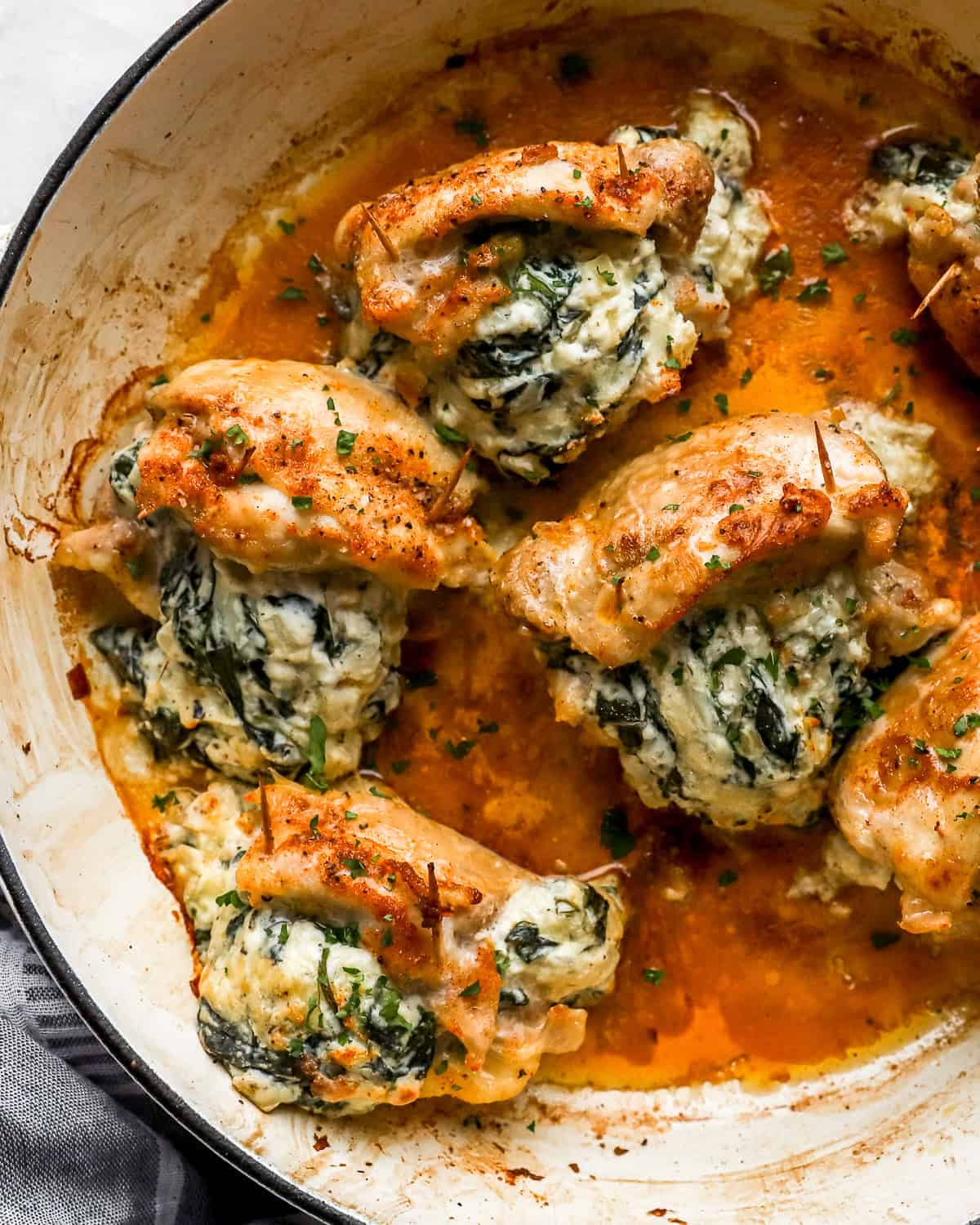 overhead view of stuffed chicken thighs in a skillet.