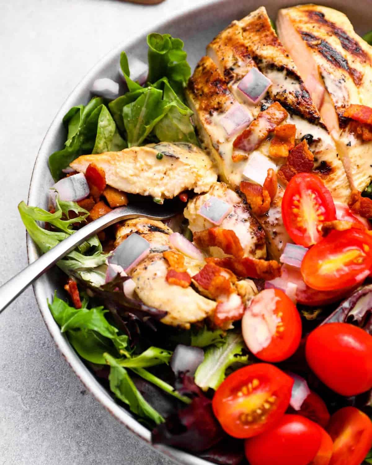 closeup of a sliced honey mustard chicken breast on a salad with a fork.