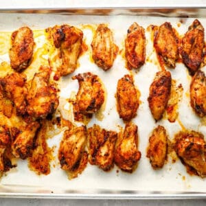 baked seasoned chicken wings on a lined baking sheet.