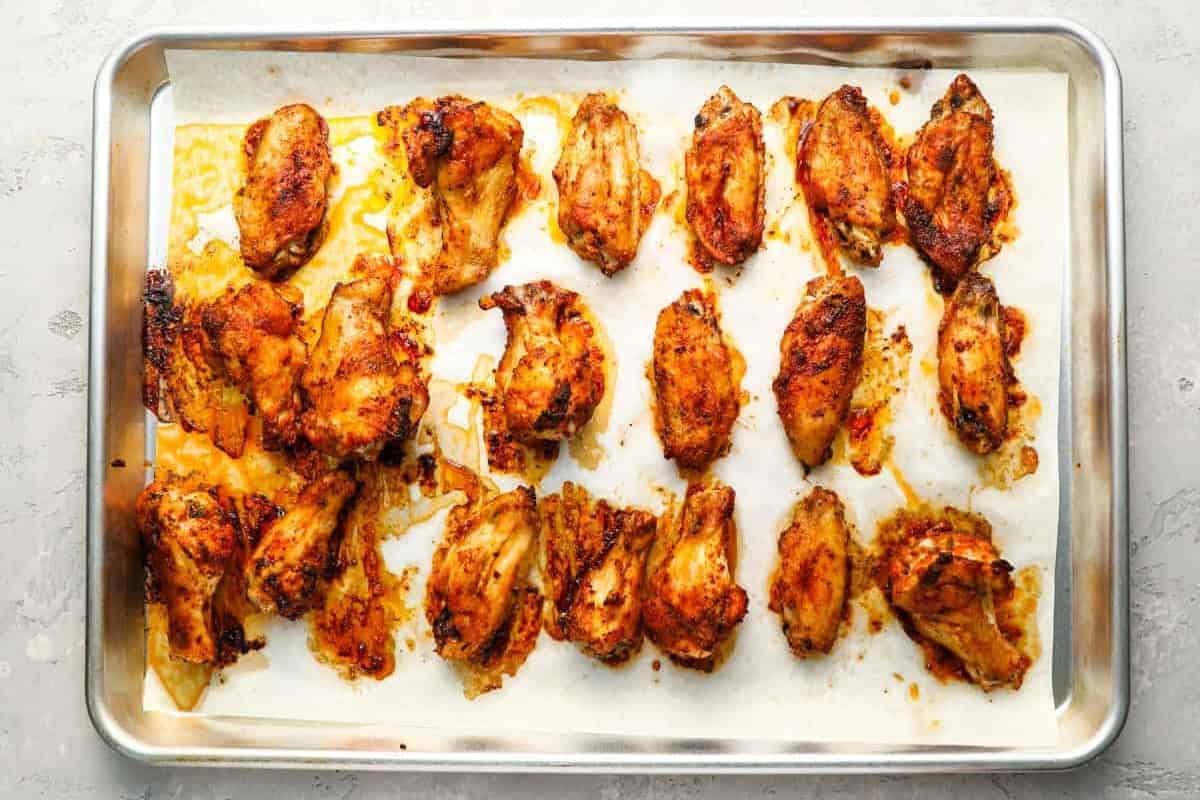 baked seasoned chicken wings on a lined baking sheet.