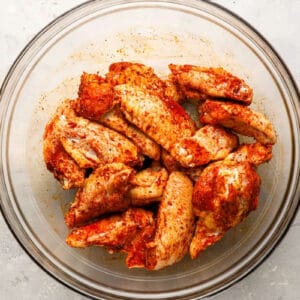raw seasoned chicken wings in a glass bowl.