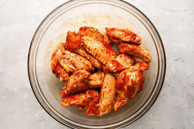 raw seasoned chicken wings in a glass bowl.