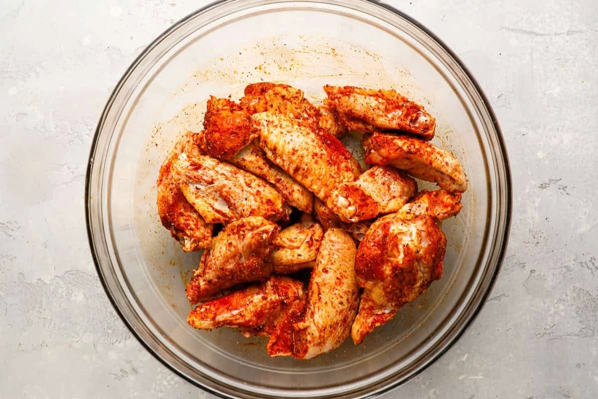 raw seasoned chicken wings in a glass bowl.
