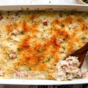 overhead view of a baked chicken cordon bleu casserole with a wooden spoon.