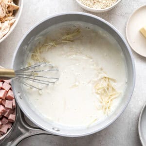 stirring cheese into cream sauce in a saucepan.