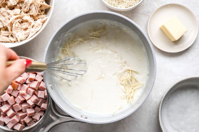 stirring cheese into cream sauce in a saucepan.